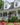 Brick house with a porch and garden, featuring cardinal brackets on posts and cardinal house number plaque.