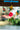 Colorful handpainted hummingbird and flower decorations hanging against a blurred natural background