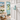 A light blue anchor-shaped wall hook made from pvc mounted on a white door opening to coastal decorated room
