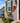 A colorful hand-painted lobster wall decor made from weather-resistant pvc, featuring a vibrant red lobster with yellow, orange, and light blue accents, mounted on a coastal home