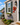 A colorful hand-painted lobster wall decor made from weather-resistant pvc, featuring a vibrant red lobster with yellow, orange, and light blue accents, mounted on a coastal home