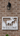 white pvc 'Welcome' sign with moose design on a brick wall.