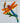 A colorful  pvc dragonfly bracket for mounting on a mailbox or porch post.  The dragonfly features bright orange wings, a red and blue head, a striped blue tail, green leaves, and a brown cattail above it.