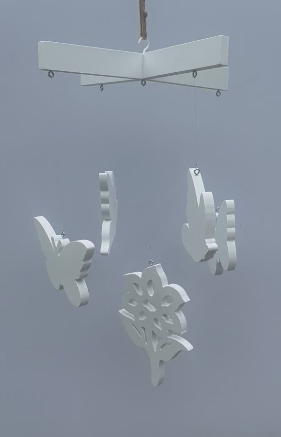 butterfly mobile featuring 4 butterflies and 1 flower made of white pvc moving slightly in the breeze; mobile is a diy kit ready for painting 