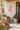pink charity ribbon wall decor on a building with pink flowers and a bench
